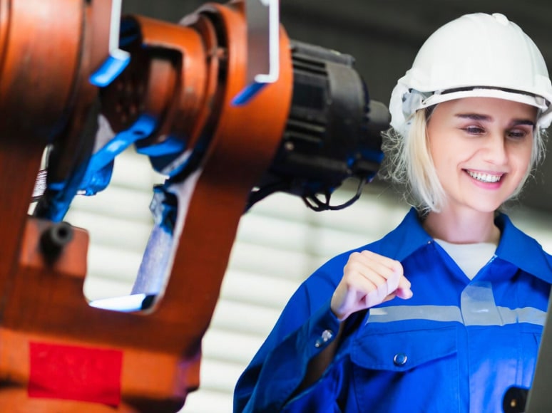 Engineer beside an industrial robotic arm on a production floor